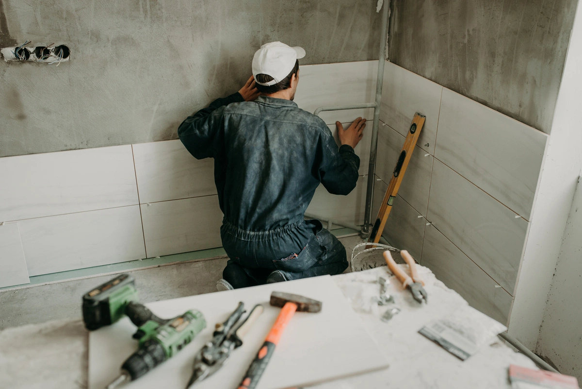 Installation de carrelage mural par un professionnel de la rénovation de salle de bain, garantissant une finition impeccable et durable.